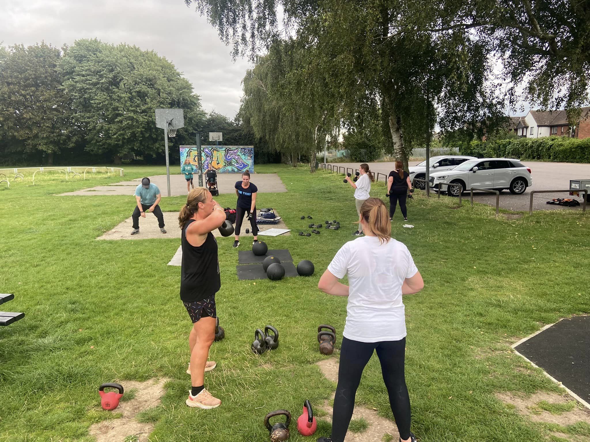Group2 Group of adults fitness training outdoors. Kettlebells, weights, slam balls.